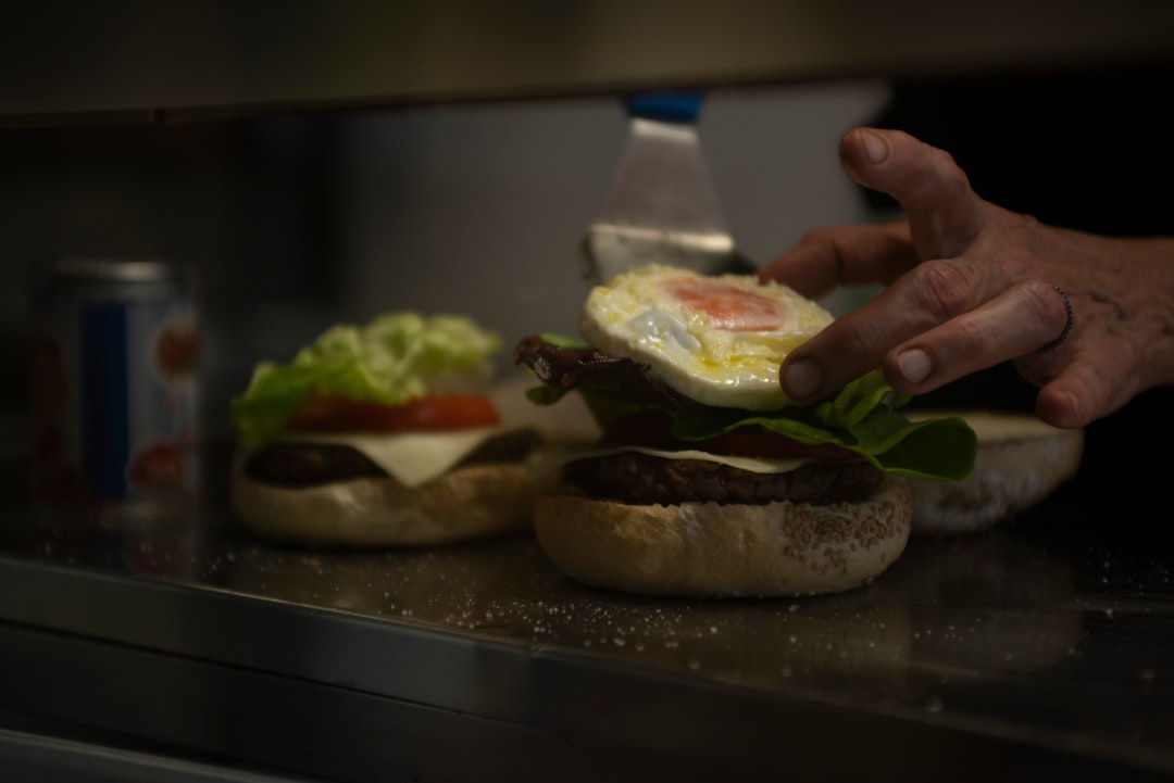 a person putting an egg in a hamburger