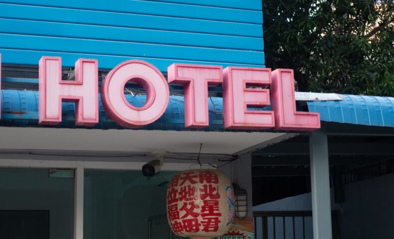 a blue building with a neon sign that says hotel