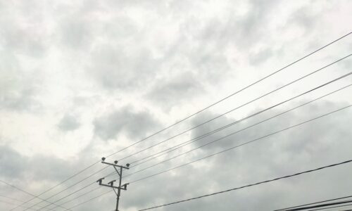 a telephone pole and power lines against a cloudy sky
