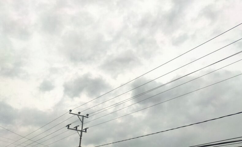 a telephone pole and power lines against a cloudy sky