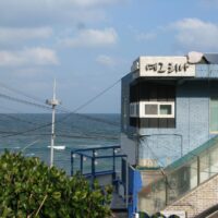 a blue building with the ocean in the background